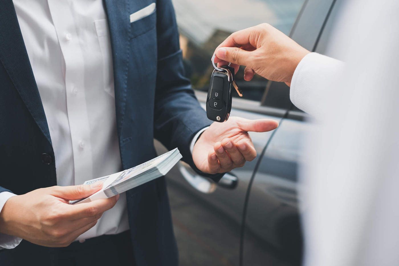 closeup photo of two hands exchanging car keys and cash.jpg.optimal